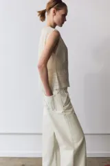 Blusa sin mangas de cuello redondo, confeccionada con detalles de encaje y puntilla a tono. Presenta cierre frontal con botones y diseño estructurado.