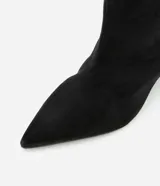 Bota de caña media con taco tipo anabela, confeccionada en gamuza sintética color negro. Presenta puntera fina, cierre lateral y diseño elegante con estructura ajustada.