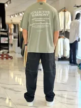 Remera oversize de color verde militar, con gran estampado tipográfico blanco en la espalda y mangas cortas.