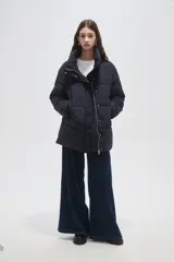 Campera puffer negra de corte holgado, con cuello alto, cierre frontal oculto y bolsillos laterales.