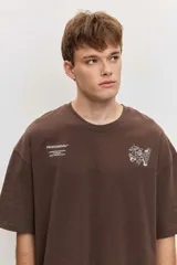 Remera marrón oversize de manga corta, con cuello redondo y pequeños estampados blancos en el pecho.