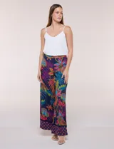 Pantalón pull on largo de caída fluida, cintura alta con pretina trasera elastizada, pierna de corte ancho tipo palazzo y detalle de guarda geométrica sobre el ruedo inferior, con estampado floral multicolor sobre base azul.