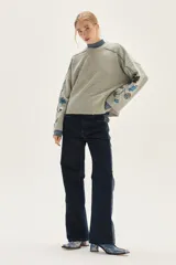 Sweater de punto color gris con cuello redondo, mangas amplias y diseño floral bordado a mano en las mangas.