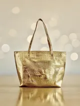 Bolso shopper de cuero color dorado con textura crocco, asas de hombro en tono semi natural y cierre superior. Cuenta con diseño espacioso, bolsillo interior y detalle artístico exclusivo de la marca.