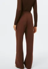 Pantalón de corte recto y holgado, color blanco, con cintura elástica y cordón ajustable. Presenta costuras verticales frontales que estilizan la silueta.