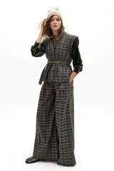 Chaleco sin mangas con diseño capitoneado y estampado a cuadros en tonos verdes y azules. Presenta cuello en V amplio, hombros estructurados y lazo ajustable en la cintura con pasadores.