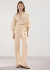 Jeans de corte recto y tiro medio color beige, confeccionados en 100% algodón, con diseño clásico de cinco bolsillos y trabillas para cinturón.
