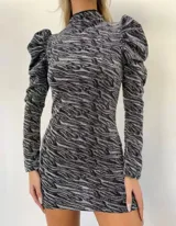 Vestido corto de lurex con estampado animal print en tonos grises y negros. Tiene cuello alto, mangas largas abullonadas y corte ajustado al cuerpo.