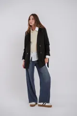 Trench color beige con doble botonadura, solapas amplias, cinturón en la cintura y presillas en los puños.