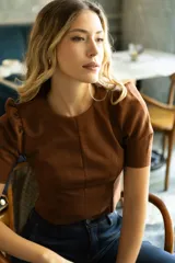 Top corto color verde militar, marca Tahari, confeccionado en símil gamuza. Tiene mangas cortas abullonadas, cuello redondo y cierre invisible en la espalda.