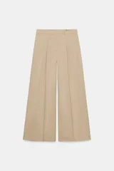 Pantalón de tiro medio con corte wide leg, confeccionado en algodón. Presenta cintura con trabillas, bolsillos laterales ocultos en costura y detalle de pliegues en el delantero. Cierre frontal con cremallera, botón y ganchos metálicos.