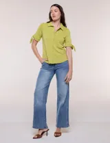Camisa blanca de manga corta con cuello solapa, cierre frontal de botones, detalles bordados al tono en el pecho y lazos para anudar en las mangas.