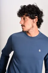 Buzo de cuello redondo en color azul, con diseño liso y logo bordado pequeño en el pecho. Presenta puños y ruedo acanalados.