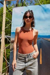 Body color marrón oscuro, confeccionado en microfibra, con escote delantero y trasero cerrado, cuerpo embolsado y gancho corsetero regulable en la entrepierna.