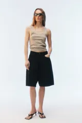 Bermuda oversize de denim color negro, con diseño de cinco bolsillos, cierre de botón y ojal, y ruedo deshilachado.