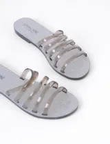 Sandalia plana plateada con base brillante y tiras transparentes.