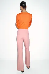 Pantalón de vestir color rosado, tiro bajo, con corte acampanado (flare) y costuras laterales marcadas. Cierre frontal con botón interior y gancho.