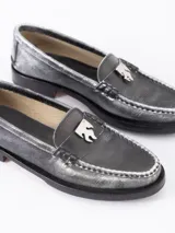 Mocasín de cuero vacuno con efecto gastado en tonos grises y negros. Presenta un aplique metálico con el logo Fire en la vincha y suela grabada con el nombre de la colaboración.