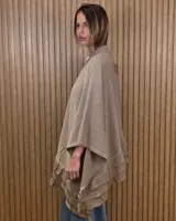 Ruana tejida de algodón en color negro, con diseño amplio y volados en el borde inferior.