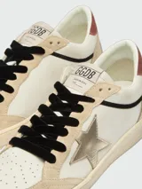 Zapatillas Ball Star de Golden Goose confeccionadas en cuero blanco, con puntera y refuerzo trasero de gamuza en tono beige, estrella lateral laminada en tono dorado y cordones negros.