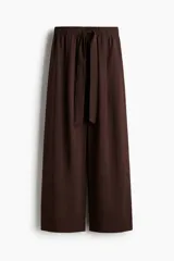 Pantalón culotte marrón chocolate de tiro alto con cintura elástica y lazo para atar. Piernas anchas con bolsillos laterales y un bolsillo decorativo en la parte trasera.
