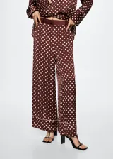 Pantalon palazzo de tejido satinado color bordó con estampado de lunares blancos. Presenta tiro medio, cintura elástica, bolsillos laterales y detalle de ribete en el ruedo.