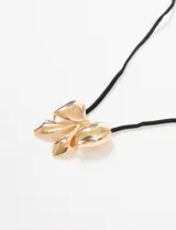 Collar con dije de moña dorada y cordón fino negro.