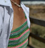 Bañador enterizo asimétrico con diseño de rayas horizontales en tonos verdes y rosas sobre tejido de lurex brillante. Cuenta con un solo tirante fino y forro interior.