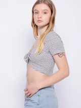 Top de manga corta con escote en V y fruncido ajustable con lazo en el centro, de tela texturizada con estampado de puntos pequeños.