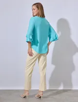 Blusa celeste de tejido piqué con mangas 3/4 y volados en los puños.