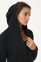Campera negra con capucha y cierre frontal, confeccionada en rústico de algodón.