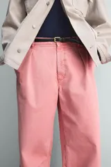 Pantalón relaxed fit color rosado, confeccionado en tejido de algodón con efecto lavado. Presenta pliegues frontales, bolsillos delanteros y bolsillos traseros de vivo. Cierre frontal con cremallera y botón.
