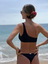 Top de bikini de lycra celeste con un solo hombro y argolla de madera decorativa.