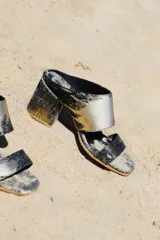 Sandalias de tacón alto con diseño de dos tiras anchas, confeccionadas en tela con estampado abstracto en tonos dorados y negros. Presentan un tacón cuadrado forrado en el mismo tejido.