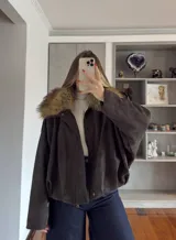 Campera tipo bomber de gamuza en color marrón oscuro, con cuello de piel sintética desmontable, cierre frontal y diseño holgado.