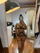 Conjunto de lencería de cuatro piezas compuesto por bralette, tanga, portaligas y ligas. Confeccionado en lycra beige con detalles de encaje negro en los bordes y tiras elásticas decorativas.