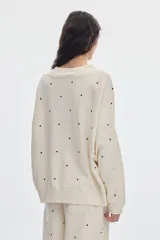 Buzo de felpa sin frisa color marfil con estampado de lunares negros, escote en V y diseño holgado.
