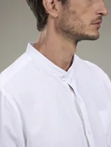 Camisa de lino blanca de manga larga con cuello mao, cierre frontal con botones y un bolsillo aplicado en el pecho.