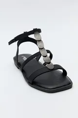 Sandalias planas color beige con tiras finas y aplique metálico central.