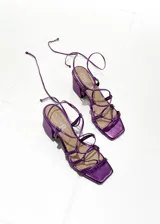 Sandalias de tacón cuadrado color fucsia metalizado, con tiras finas que se atan alrededor del tobillo.