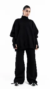 Buzo oversize de color negro con cuello alto y mangas largas tipo guante con abertura para el pulgar. Diseño holgado y deportivo.