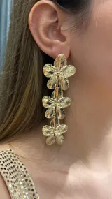 Caravanas colgantes de color dorado con diseño de tres flores superpuestas en metal texturizado.