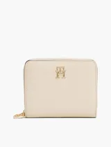 Billetera Tommy Hilfiger color crema con cierre de cremallera y logo TH dorado en el frente.