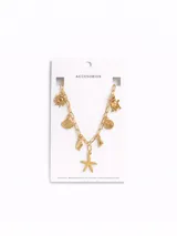 Collar dorado con cadena de eslabones alargados y múltiples dijes colgantes con temática marina, que incluyen una estrella de mar, conchas marinas, un sol y una tortuga.
