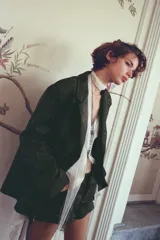 Blazer verde militar de efecto gamuza, con cuello de solapa, manga larga, bolsillos delanteros con solapa, forro interior y cierre frontal con botones.