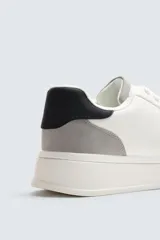 Zapatillas deportivas blancas con detalle de color gris en el talón y suela con volumen.
