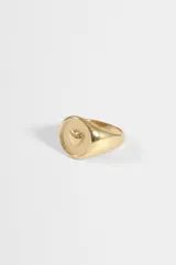 Anillo de acero quirúrgico dorado, tipo sello con un relieve en forma de corazón en el centro.