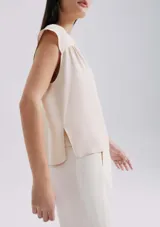 Blusa naranja sin mangas con escote en V y detalle de frunces en los hombros.