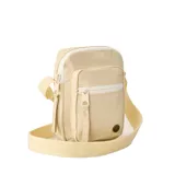 Morral pequeño tipo bandolera de Rip Curl, color beige, con cierre de cremallera, bolsillo frontal, correa ajustable y logo metálico circular en la parte inferior.