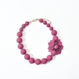 Collar de cuentas redondas color fucsia con dije de flor fucsia y detalles de strass.